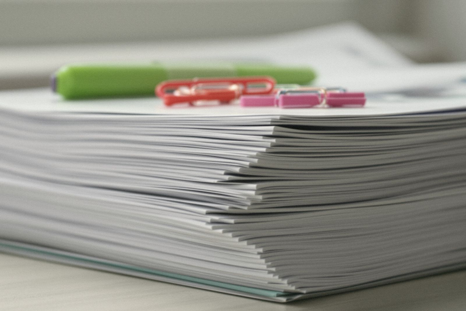 Épaisse pile de documents imprimés avec trombones colorés et surligneur vert