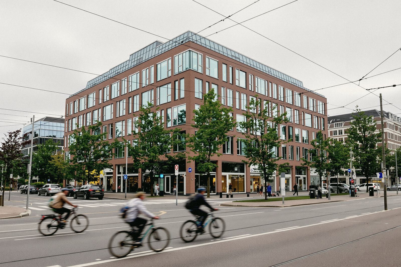 Immeuble de bureaux en brique et verre à un carrefour d'une ville européenne, cyclistes flous au premier plan